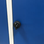Pomo negro en poliamida para cerrar la taquilla con candado, en puerta metálica azul